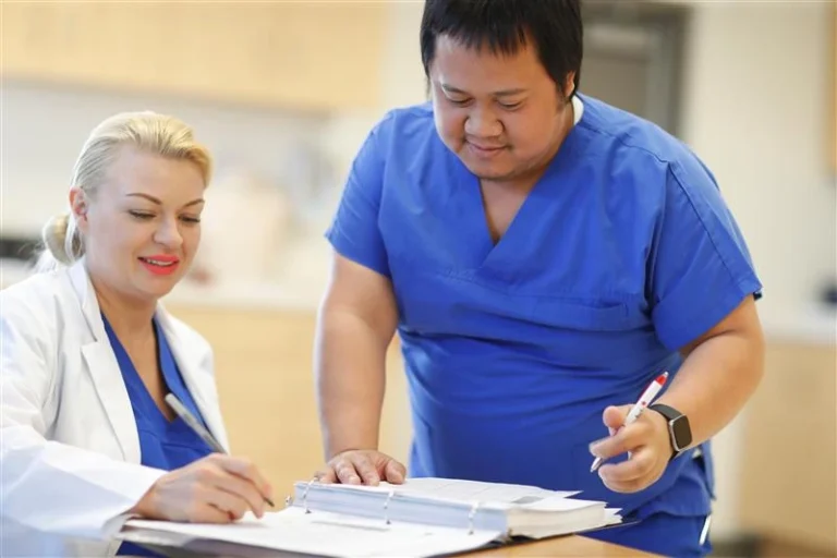 Experience at Oulton College our Licensed Practical Nursing Program. Image has an Oulton College Practical Nursing Student in the Nursing Lab, while students are completing there Practical during a lesson.