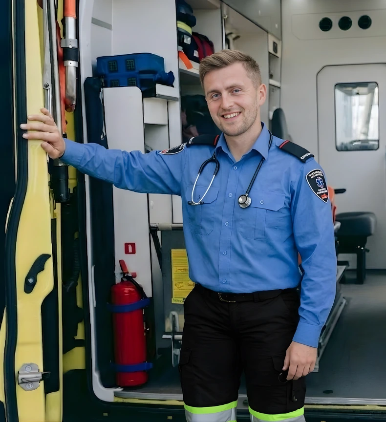 A male Primary Care paramedic student, using the paramedic uniform, standing in front of a Paramedic Vehicle.